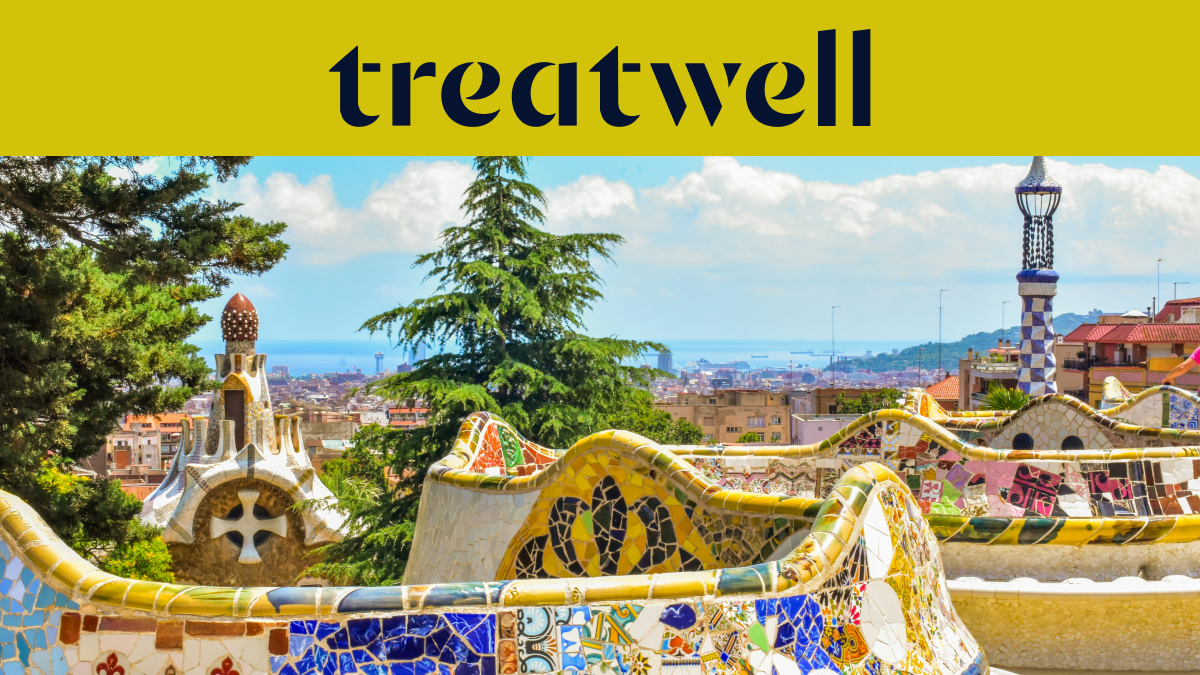 A scenic view of Barcelona from Park Güell, featuring Antoni Gaudís iconic colourful mosaic benches and fairytale-style spires in the foreground, with the city and sea beyond. A large yellow banner at the top displays the "treatwell" logo.