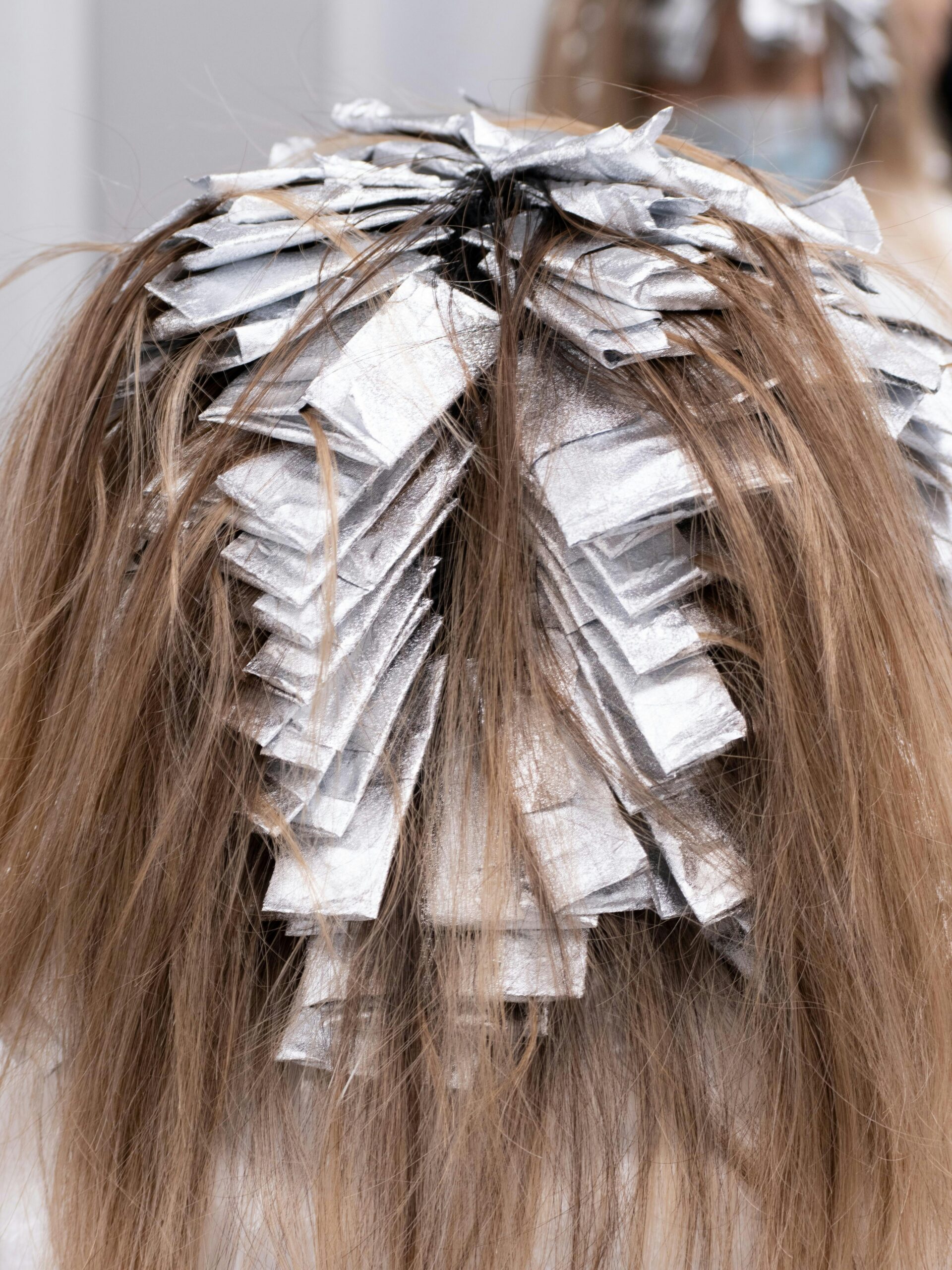 Back of a client’s head with foils in her hair who is having partial coverage colour treatment at the hairdresser’s