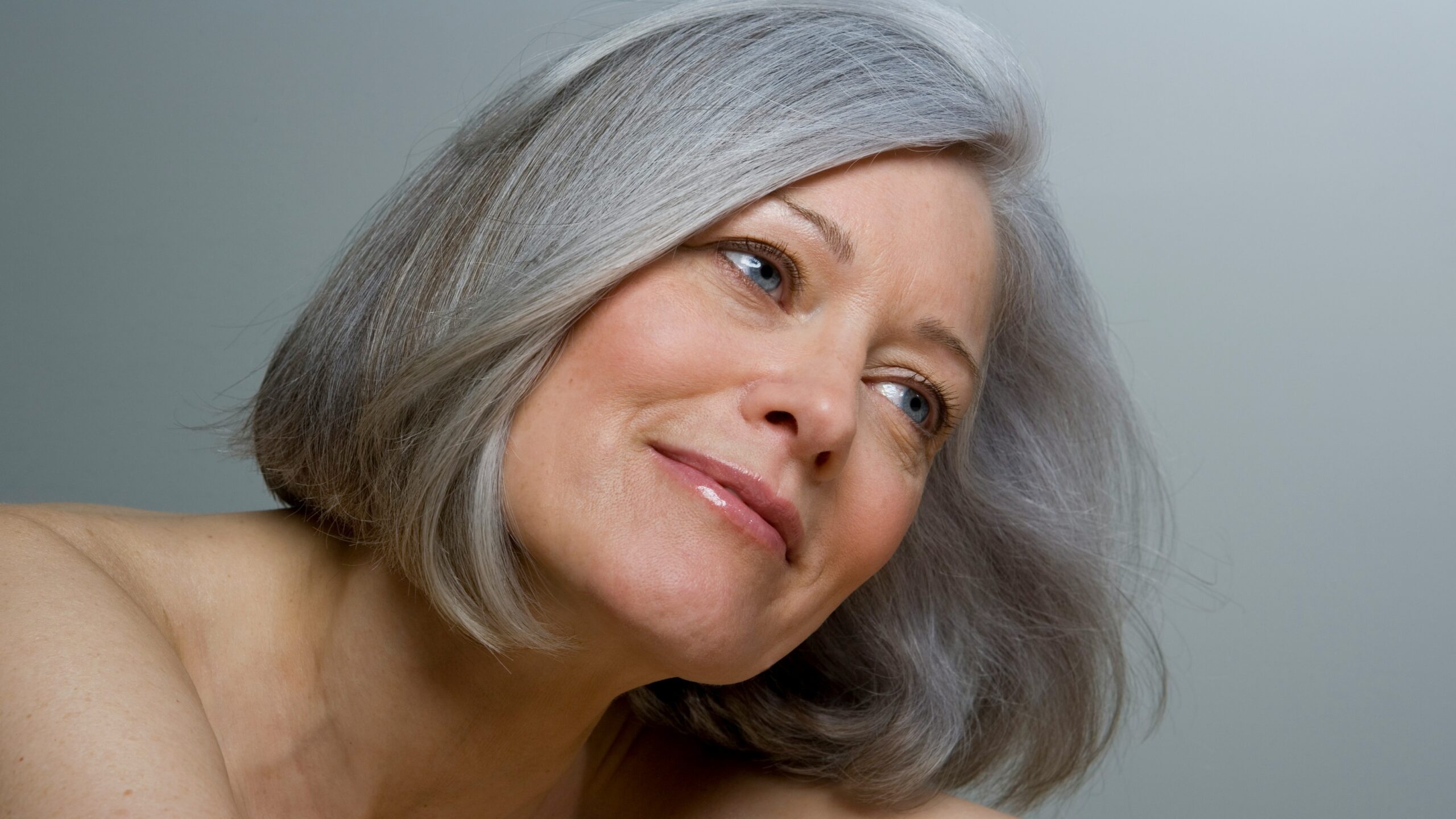 Close-up of a woman with a smooth grey bob hairstyle and natural makeup