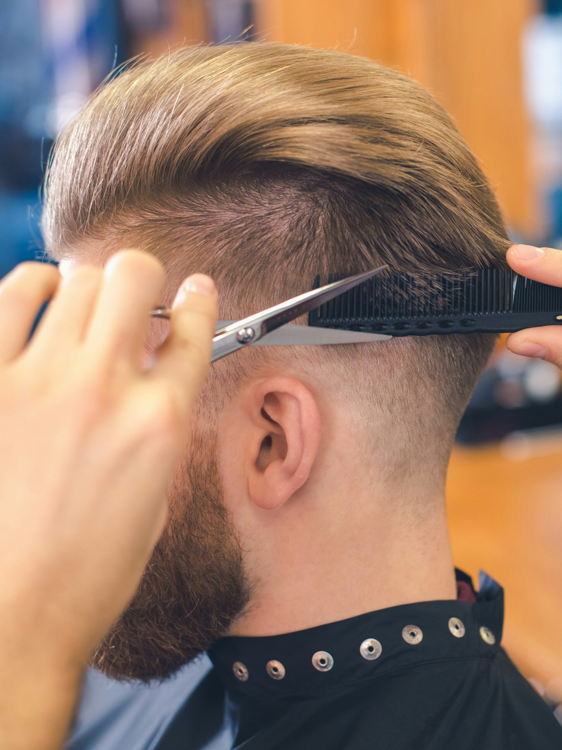 Close-up of a barber cutting a taper fade for a client using the scissors over comb technique at the back of the head