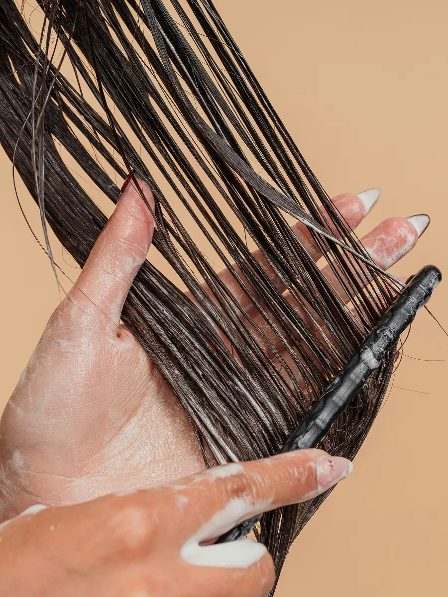 Close-up of a woman working conditioner through her long hair with a wide-tooth comb