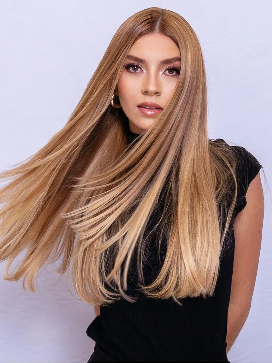 Studio portrait of woman swishing her long glossy caramel blonde hair